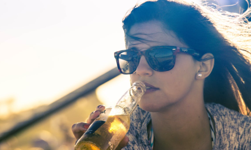 Vrouw drinkt Corona in de zon